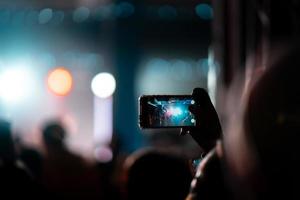 persona cerca de grabar video con teléfono inteligente durante un concierto. foto