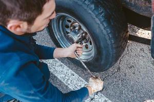 Man unscrews the bolts on the wheel photo