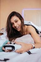 chica divertida acostada en la cama y jugando videojuegos, sosteniendo el controlador foto