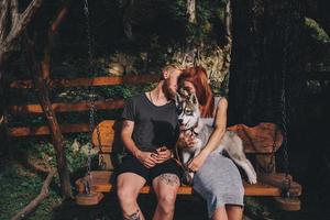 beautiful couple together with dog on a swing photo