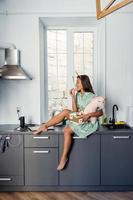 Young pretty woman eating cake in modern kitchen. photo