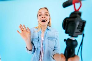 Beautiful girl blogger relieves itself at camera isolated blue background photo