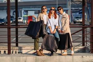 mujeres jóvenes con bolsas de compras en una parada de autobús foto