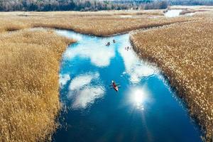 Group of people in kayaks among reeds on the autumn river. photo