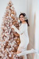 Young woman in an elegant dress near the Christmas tree photo