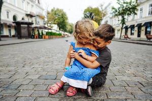 niño y niña están sentados en la calle foto