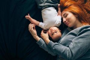 feliz madre con bebé acostado juntos en la cama foto