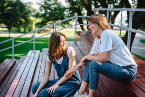 dos hermosas mujeres jóvenes descansando en un banco foto