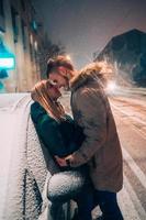 Young adult couple kissing each other on snow covered street photo