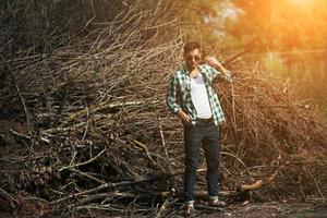 The man in the authentic boots and selvedge jeans  on a the background of branches photo