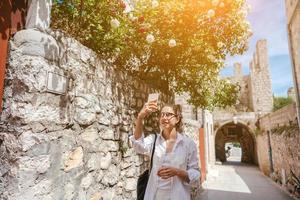 Young girl walking through ancient narrow streets and takes a picture photo