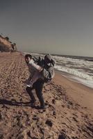 el hombre lleva a su novia en la espalda, pareja divirtiéndose en la orilla del mar foto