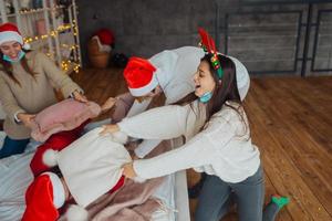 Multi-ethnic friends have fun fighting on pillows on new year's eve photo