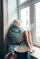 girl sitting on a window in a blanket photo