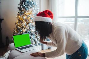 Female wearing santa hat while speaking with online friend on laptop photo