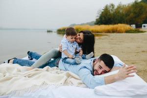 familia joven feliz relajándose juntos en el lago foto