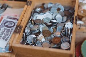 Old coins of different denominations are in a small wooden box photo