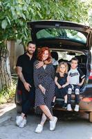 familia feliz posando en cámara cerca del auto foto