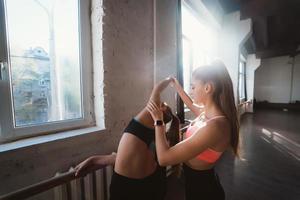 Active sportive woman stretching, young woman helping her photo