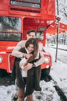 young guy warms his beautiful girl with jacket on a snowy street photo