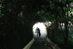 couple walking through the tunnel of trees photo