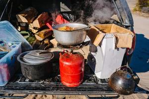 sopa hirviendo en el quemador, cocinando comida al aire libre con chorro de gas foto