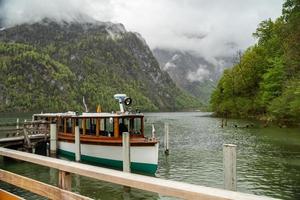 vista panorámica del lago konigssee con muelle de madera con barco turístico amarrado foto
