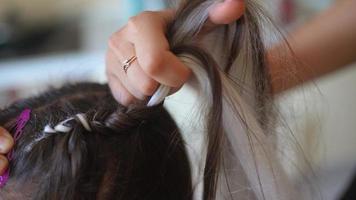 Process of braiding. Master weaves braids on head in a beauty salon, close up photo