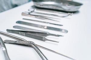 varios instrumentos quirúrgicos yacen sobre una mesa blanca foto