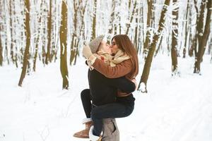 guy holds the girl on hands in snow park photo