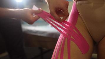 Physiotherapist applying kinesio tape on female patient. photo