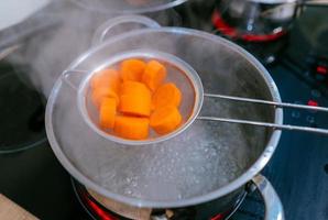 The image of a small amount of chopped carrots over a boiling pan photo