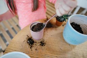 Little girl digs up the ground for rosetting with a spoon photo
