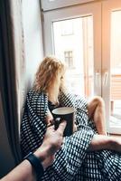 girl sitting on a window in a blanket photo