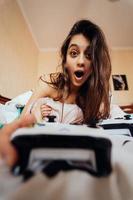 Funny girl lying in bed and playing video game, holding controller photo