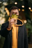 Handsome guy holding autumn leave in the park photo