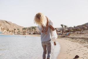 A guy carrying a girl, at the beach photo