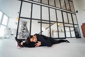 Young female wearing black sports suit exercising yoga pose indoors. photo