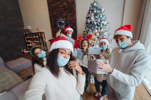 Multiethnic group of friends in Santa hats with gifts in hands. photo