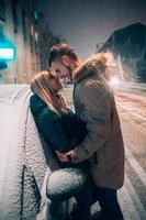 Adulto joven pareja besándose en la calle cubierta de nieve foto
