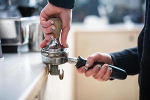 Barista presses ground coffee using tamper. photo