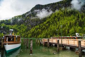 vista panorámica del lago konigssee con muelle de madera con barco turístico amarrado foto