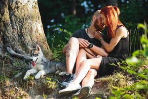 hermosa pareja sentada en un bosque cerca del árbol foto