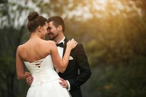 la novia y el novio bailan juntos en el bosque foto