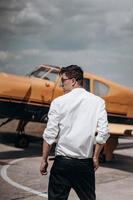 A man standing on the background of a small single engine plane. photo