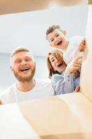 familia feliz recién mudada a una casa nueva y mirando la caja foto