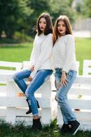 Two girls lean bench photo
