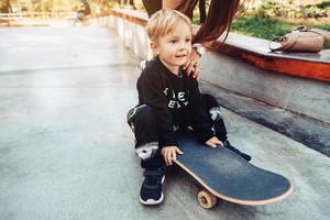 Young kid sitting in the park on a skateboard. photo