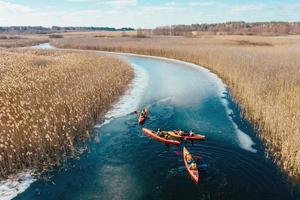 grupo de personas en kayaks entre juncos en el río de otoño. foto