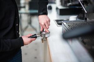 Barista presses ground coffee using tamper. photo